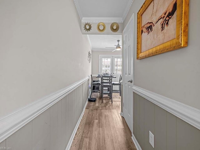 hall with a wainscoted wall, crown molding, and wood finished floors