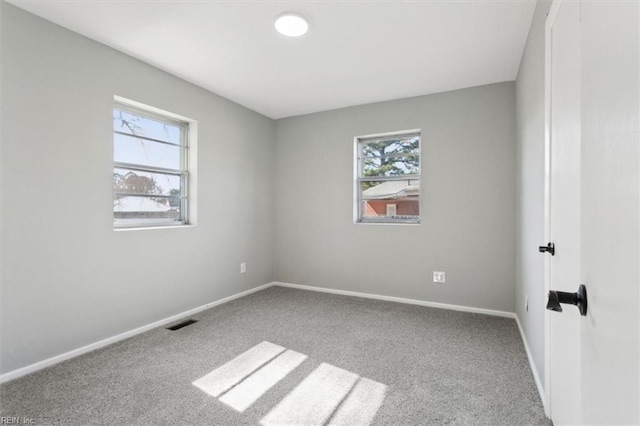 empty room with carpet floors, visible vents, and baseboards