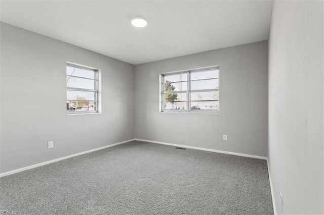 carpeted spare room with visible vents and baseboards