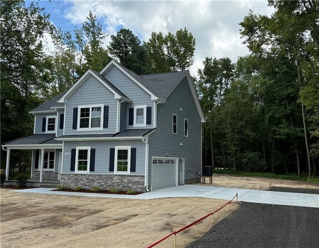 craftsman-style home with an attached garage, stone siding, and driveway