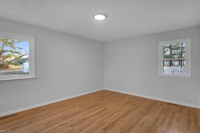 unfurnished room featuring baseboards, visible vents, and light wood-style flooring