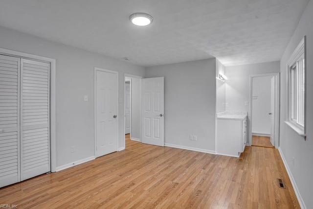 unfurnished bedroom featuring visible vents, light wood-style flooring, and baseboards