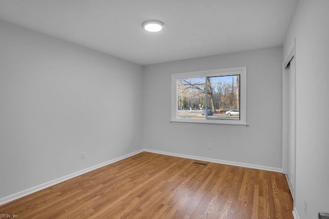 unfurnished bedroom featuring a closet, wood finished floors, and baseboards