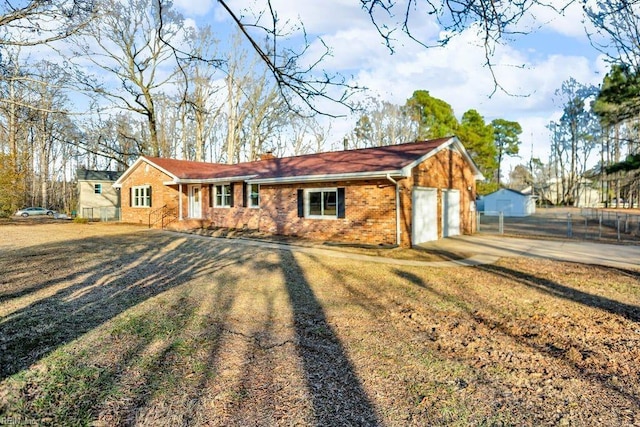 view of front of home featuring brick siding, driveway, and fence