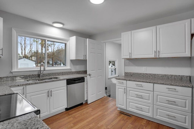 kitchen featuring stainless steel dishwasher, a sink, light wood-style floors, and white cabinets