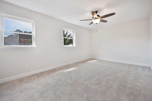 carpeted spare room with a ceiling fan and baseboards