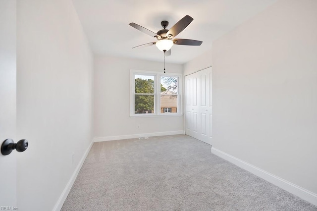 carpeted empty room featuring ceiling fan and baseboards