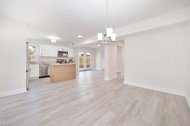 kitchen with white cabinetry, baseboards, appliances with stainless steel finishes, and open floor plan