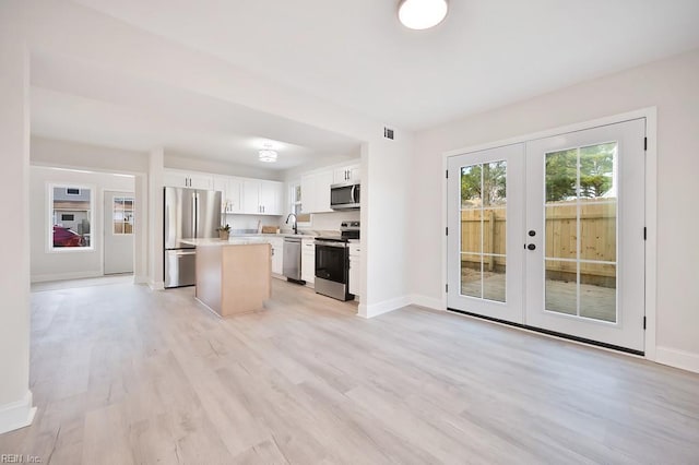 kitchen with visible vents, a center island, stainless steel appliances, light wood-style floors, and a sink