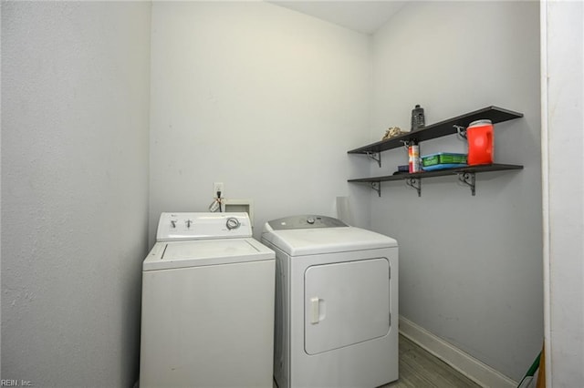 laundry room featuring laundry area, washing machine and dryer, baseboards, and wood finished floors