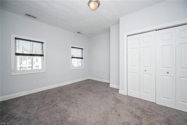 unfurnished bedroom with carpet floors, baseboards, visible vents, and a closet