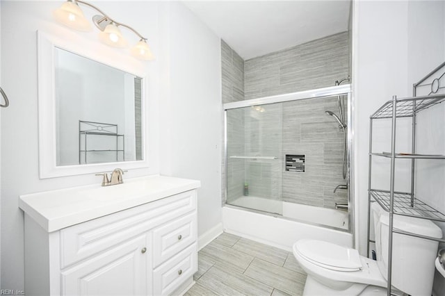 full bathroom with bath / shower combo with glass door, vanity, and toilet