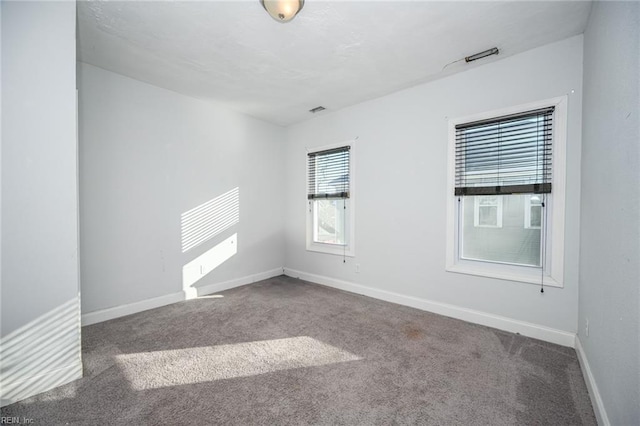 unfurnished room featuring carpet flooring, visible vents, and baseboards