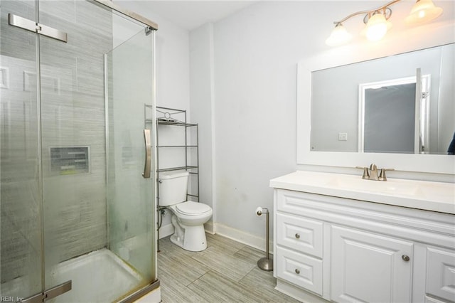 full bath with vanity, a shower stall, toilet, and baseboards