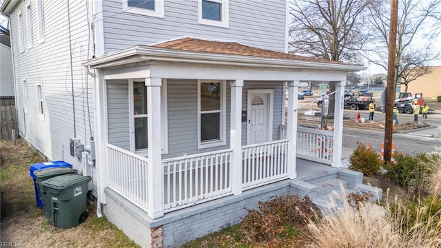 exterior space with a porch and a shingled roof