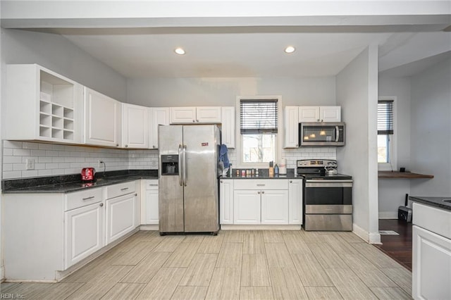 kitchen with dark countertops, white cabinetry, stainless steel appliances, and decorative backsplash