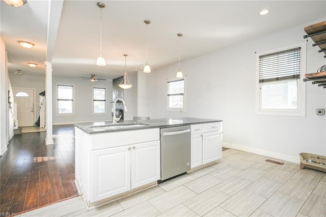 kitchen with a sink, a healthy amount of sunlight, white cabinets, and stainless steel dishwasher