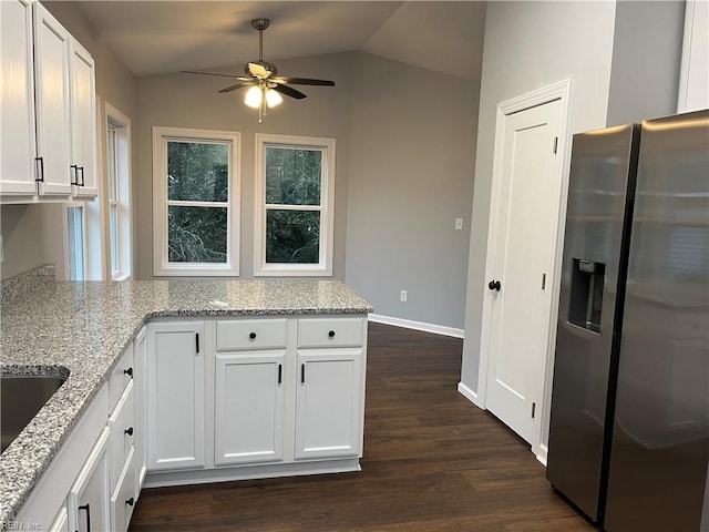 kitchen with stainless steel fridge, light stone counters, white cabinets, and dark wood finished floors