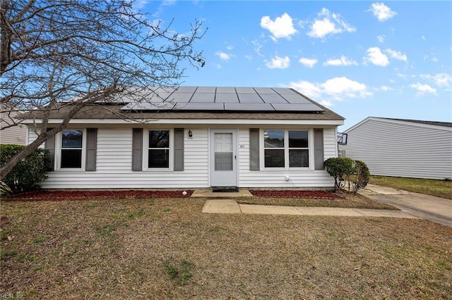 view of front facade with a front yard, roof with shingles, and solar panels