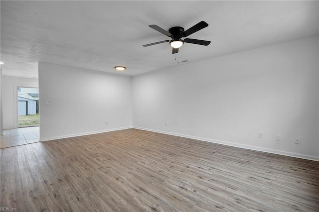 empty room featuring a ceiling fan, baseboards, and wood finished floors