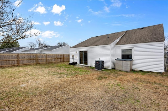 back of house with a yard, a shingled roof, cooling unit, and fence private yard