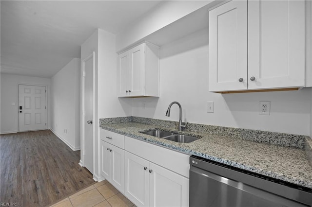 kitchen with white cabinetry, a sink, stainless steel dishwasher, and light stone countertops