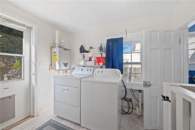 clothes washing area with marble finish floor, washer and clothes dryer, water heater, a sink, and laundry area