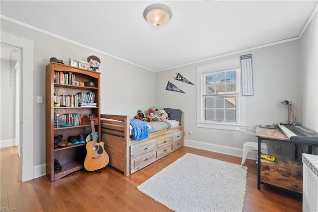 bedroom featuring baseboards, wood finished floors, and crown molding