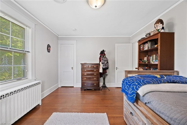 bedroom with radiator, baseboards, crown molding, and wood finished floors