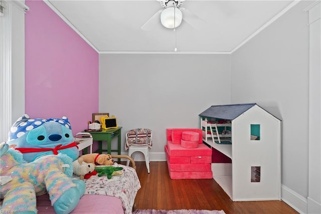 recreation room featuring ornamental molding, ceiling fan, baseboards, and wood finished floors