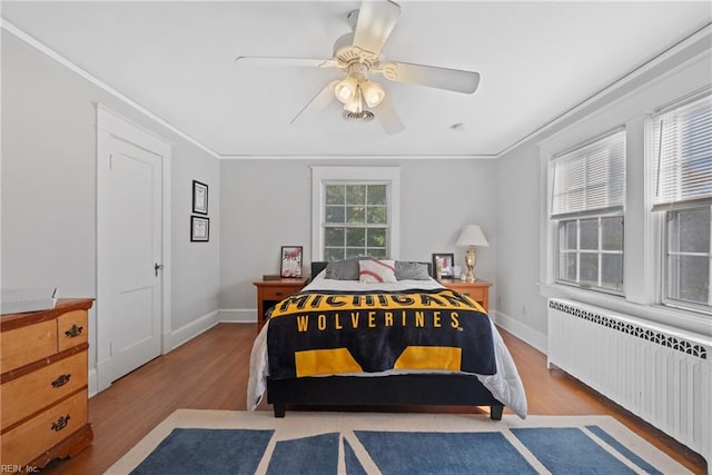 bedroom featuring baseboards, crown molding, radiator heating unit, and wood finished floors