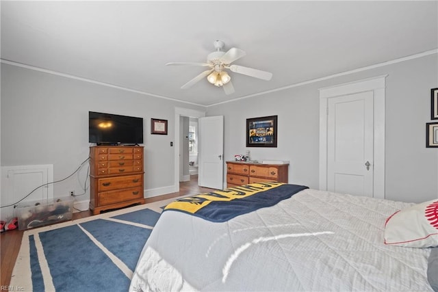 bedroom featuring ornamental molding, a ceiling fan, baseboards, and wood finished floors