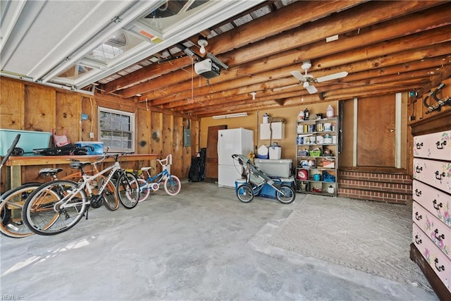 garage with a garage door opener, freestanding refrigerator, and electric panel