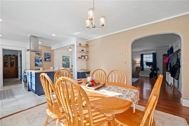 dining space featuring baseboards, arched walkways, ornamental molding, light wood-type flooring, and a chandelier