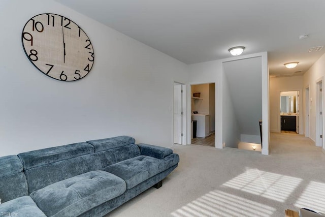 living area with light carpet, washer / clothes dryer, and visible vents