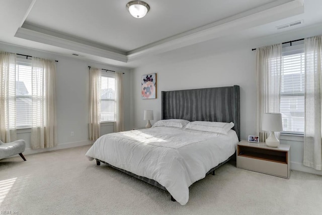 bedroom with carpet floors, a raised ceiling, visible vents, and baseboards