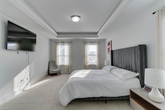 carpeted bedroom featuring baseboards and a tray ceiling