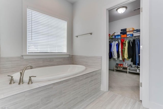 full bath with a spacious closet, visible vents, and a bath