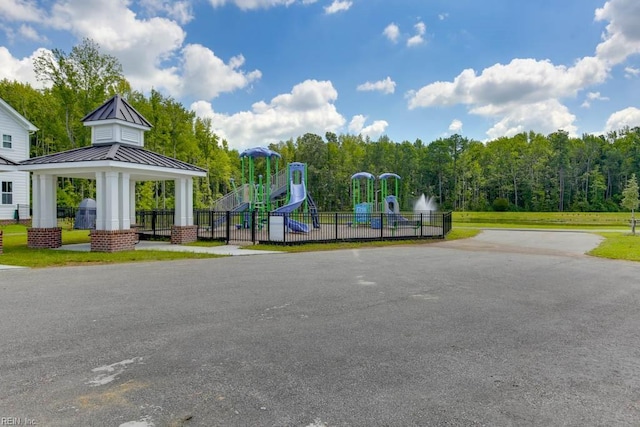 community playground featuring fence, a view of trees, and a gazebo