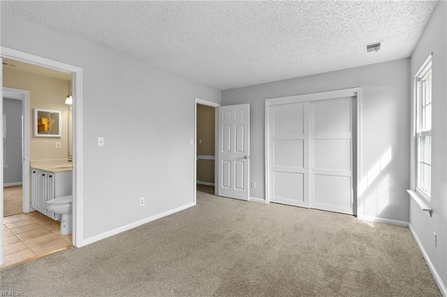 unfurnished bedroom featuring baseboards, visible vents, connected bathroom, carpet flooring, and a closet