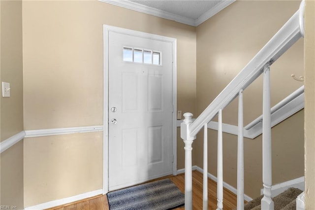 entryway featuring ornamental molding, stairway, wood finished floors, and baseboards