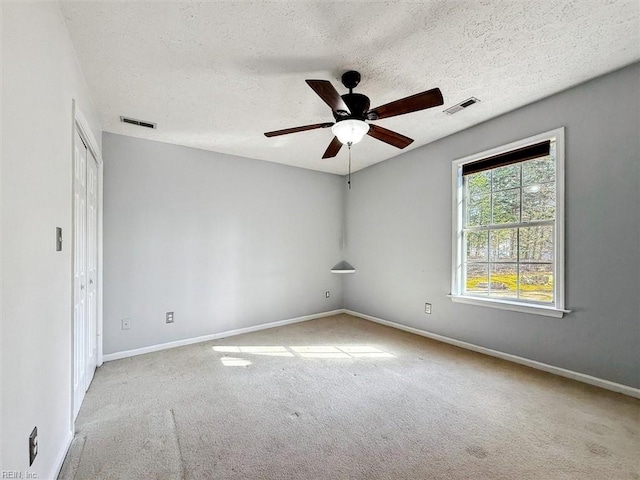 unfurnished room with a textured ceiling, visible vents, and carpet flooring