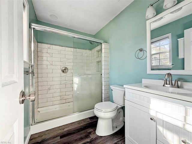 bathroom featuring toilet, a stall shower, wood finished floors, and vanity