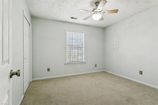 unfurnished room with light carpet, a textured ceiling, visible vents, and baseboards