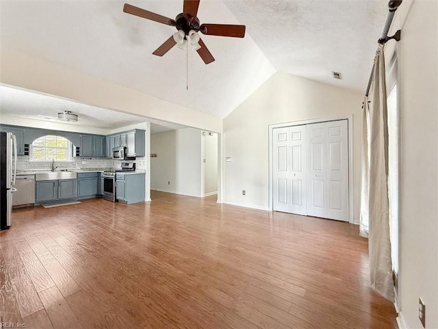 unfurnished living room with visible vents, light wood-style floors, a sink, ceiling fan, and baseboards