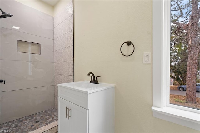 bathroom with tiled shower and vanity