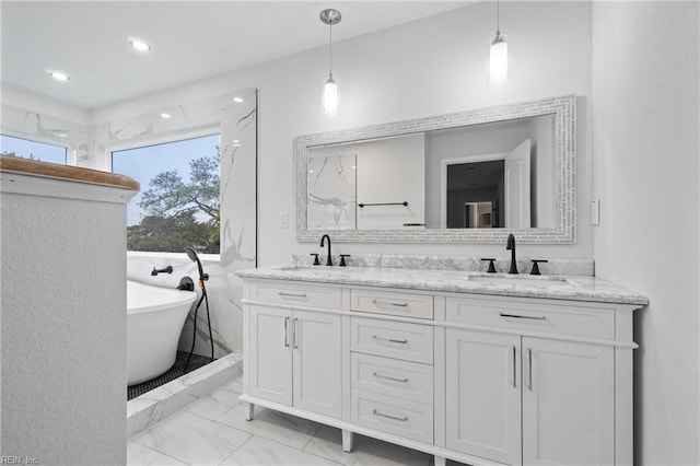 full bath featuring marble finish floor, double vanity, a freestanding tub, and a sink