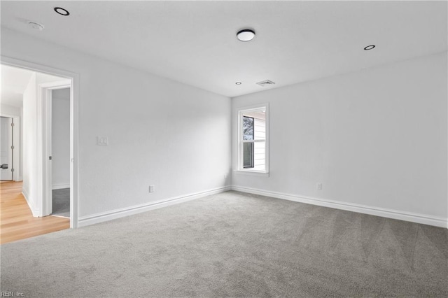 carpeted empty room featuring recessed lighting, visible vents, and baseboards