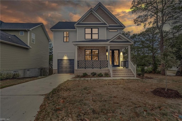 view of front of home with covered porch, driveway, brick siding, and a garage