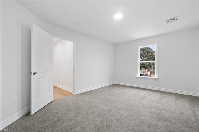 carpeted spare room with visible vents and baseboards